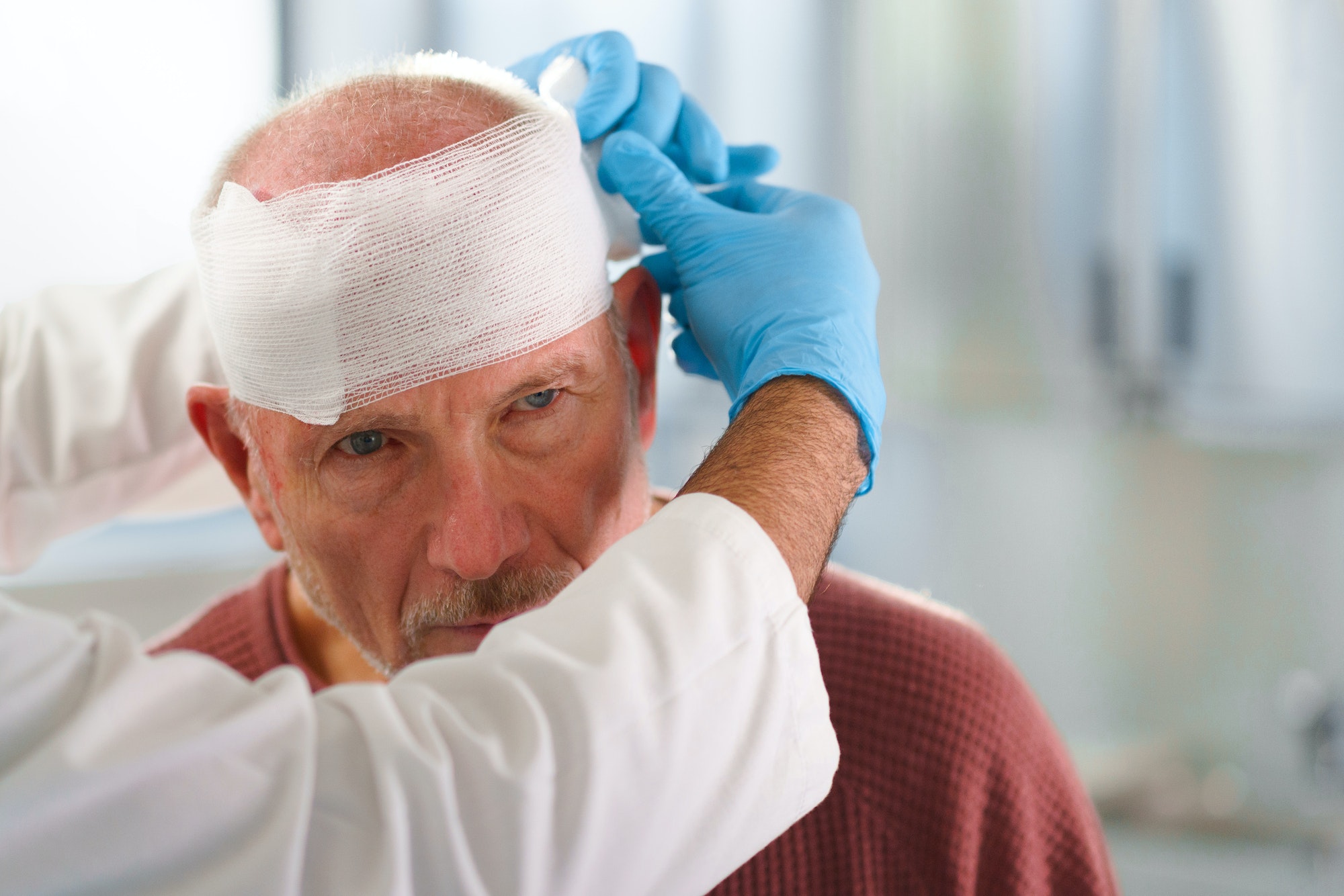 Close-up of doctor treating injury of senior man.
