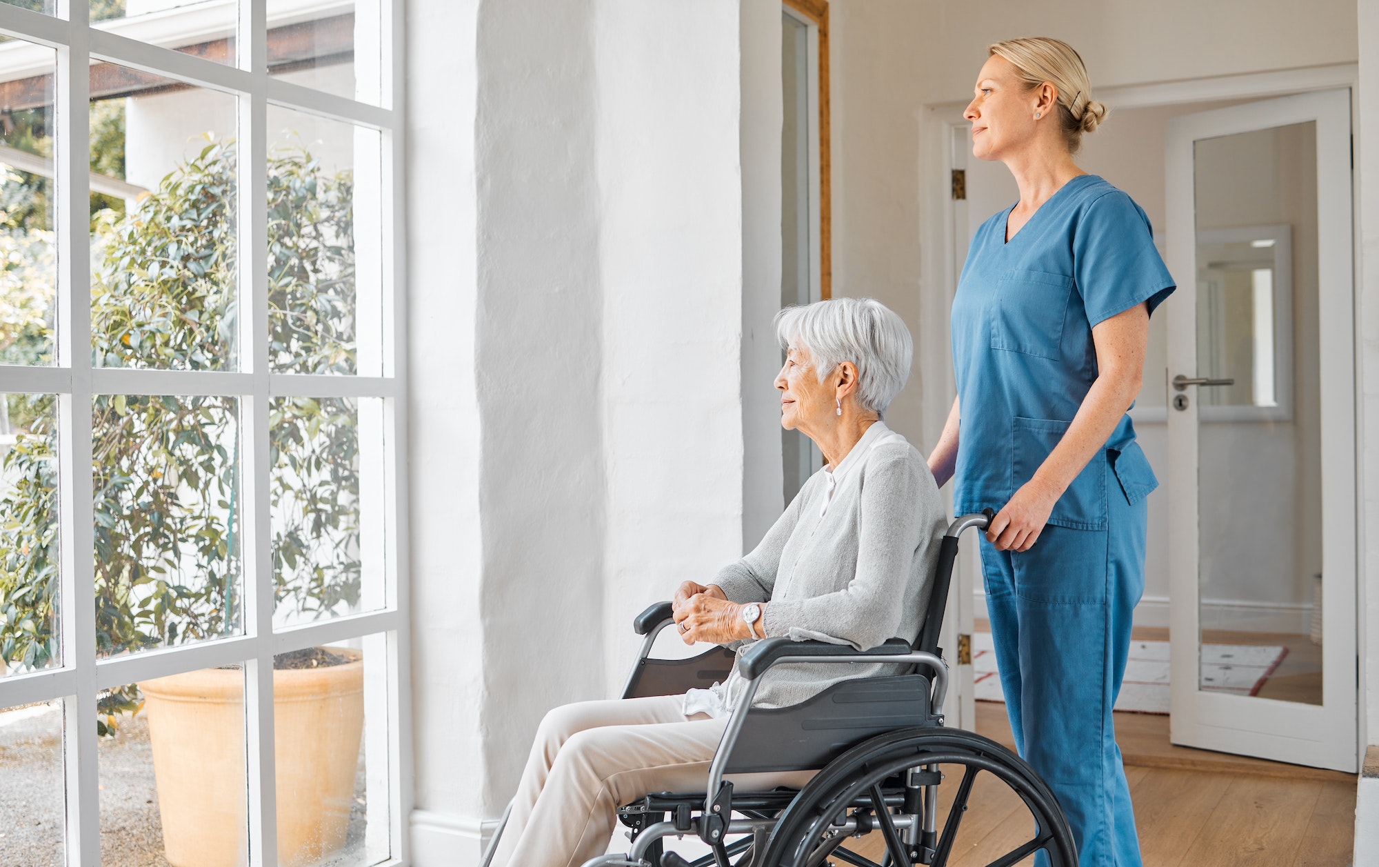 Shot of a nurse caring for a senior woman in a wheelchair in a retirement home